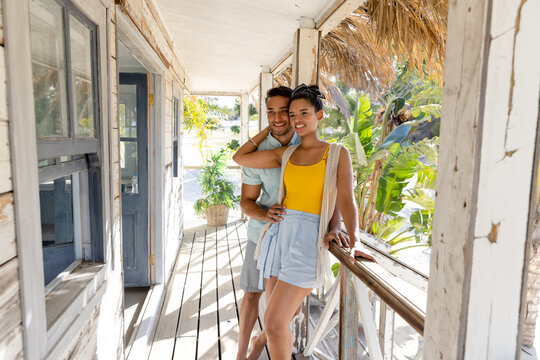 Romantic caucasian young couple looking away while standing by railing in cottage balcony