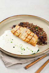 Portion of halibut fillet with soba noodles and creamy sauce