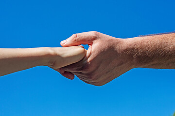 children's and man's hand hold each other against the blue sky. Help the girl. Social care for children