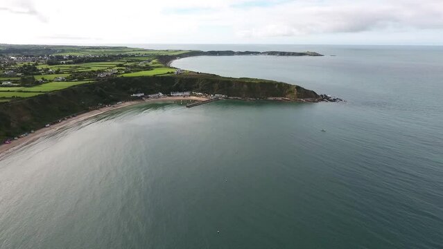 Aerial view approaching the harbour and beach huts at Nefyn with Porthdinllaen in the distance situated on the Llyn Peninsula in North Wales.