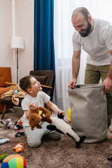 Father and little boy clean up toys - 610948418