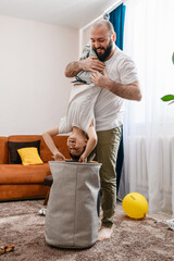 Father and son have fun at home, boy upside down.