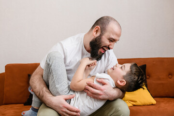 Father hug little boy at home sofa