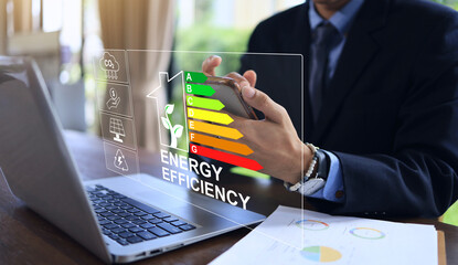 Businessman using smart phone home's energy efficiency rating label, which the energy efficiency of...