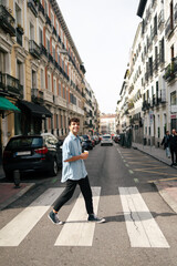 Young man crossing the road in city