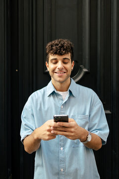 Young man with curly hair using smartphone