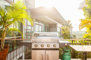 Modern luxury patio with a large grill for summer barbecues in a backyard deck. The gas BBQ and stylish furniture provide a perfect setting to cook, relax, and enjoy the outdoors.