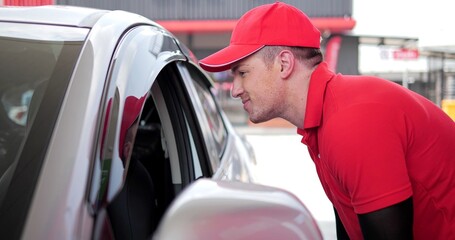 Gas station service. Caucasian male worker in red uniform talking to customers driver in car come to the service at gas station. Transportation power business concept