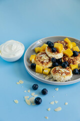 Breakfast with cheesecakes and berries on blue background