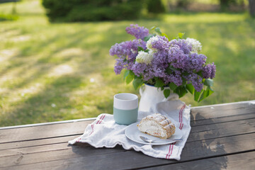 Little coffee time with a piece of cake and beautiful flowers on a terrace in a green garden.