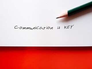 paper note on orange background with handwritten text COMMUNICATION IS KEY, means communication is...