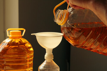 A man pours sunflower oil from a large bottle. Hand holding bottle with oil pouring