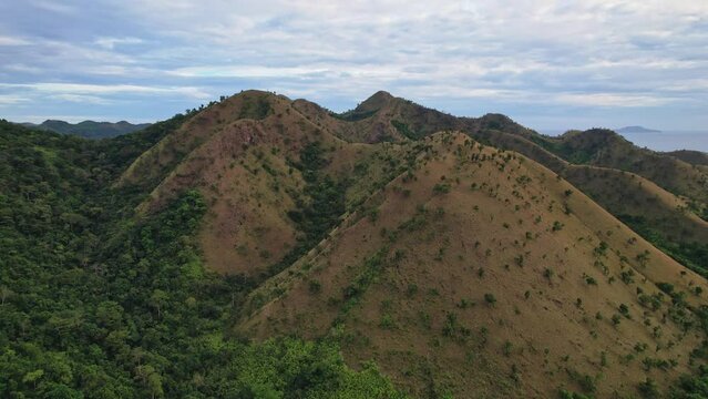 Drone footage of Philippines Mountains. We can see beautiful green and yellow mountains or hills sourrounded by endless sea.