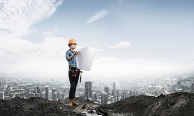 Obraz premium Female engineer in hardhat standing with blueprint