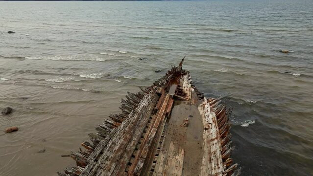 Abandoned shipwreck, An abandoned broken boat full of holes lying on the seashore. Wreck ship on reefs in sea or ocean. The sunken ship, the ship ran aground. Ecological disaster of the Aral Sea.