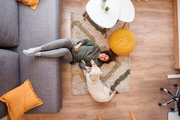 Woman and dog lying on floor spending time at home together