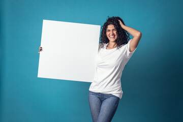 Beautiful curly woman holding blank billboard isolated on blue background