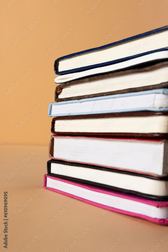 Poster close up of stack of books and notebooks with copy space on orange background