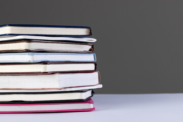 Close up of stack of books and notebooks with copy space on grey background