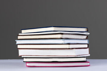 Close up of stack of books and notebooks with copy space on grey background