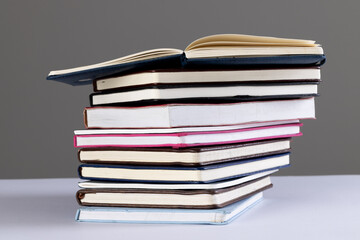 Close up of stack of books and notebooks with copy space on grey background