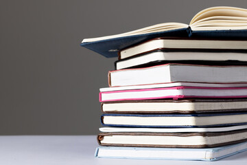 Close up of stack of books and notebooks with copy space on grey background