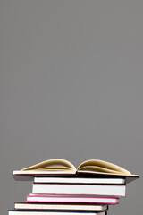 Close up of stack of books and notebooks with copy space on grey background