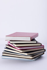 Close up of stack of books and notebooks with copy space on white background