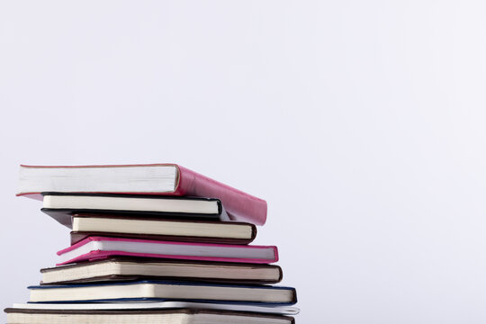 Close up of stack of books and notebooks with copy space on white background