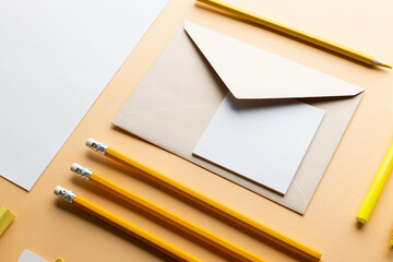 Flat lay of yellow pencils, pen and white paper with copy space on yellow background