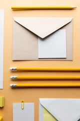 Flat lay of yellow pencils and envelope, white paper with copy space on yellow background