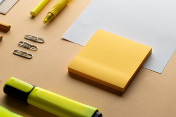 Flat lay of yellow notes, pen and highlighter and white paper with copy space on yellow background