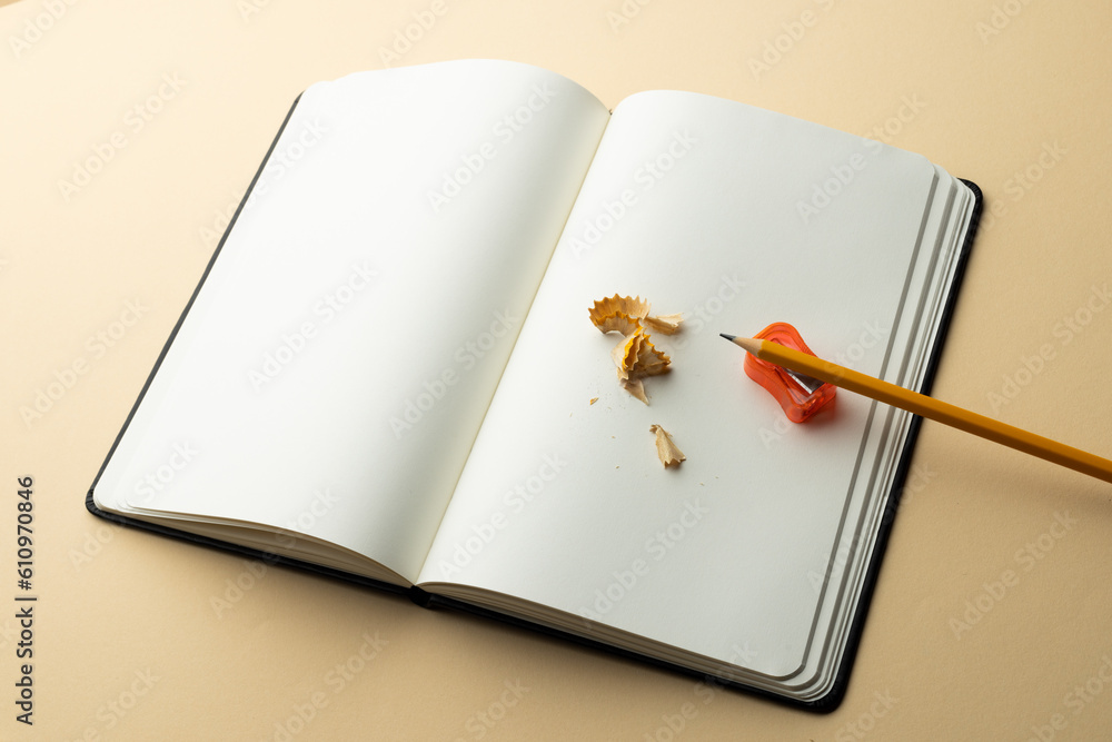 Poster close up of notebook and pencil, sharpener with copy space on yellow background