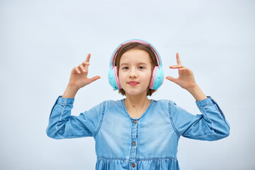 Girl teenager in casual denim dress listening to music in headphones