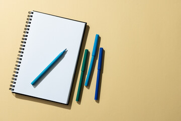 Close up of notebook and four markers with copy space on yellow background