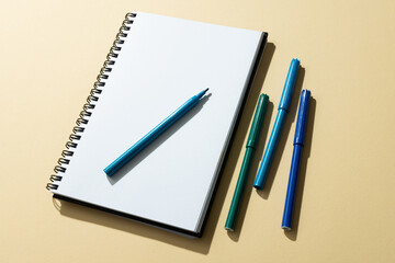 Close up of notebook and four markers with copy space on yellow background