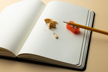 Close up of notebook and pencil, sharpener with copy space on yellow background