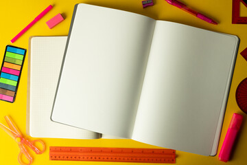 Flat lay of notebook with copy space and writing materials on yellow background