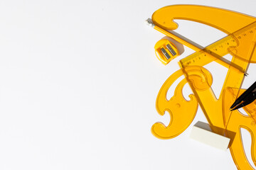 Close up of yellow rulers, compass and sharpener on white background