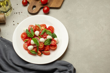 Salad with tomatoes, mozzarella and basil on a gray background