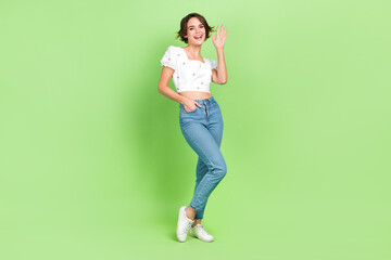 Full body photo of nice youngster lady see friends street say hi hey guys wear crop shirt jeans shoes isolated green color background © deagreez