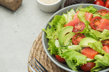 Vegetable salad with fish,  tomatoes, avocado and cucumber on a gray background