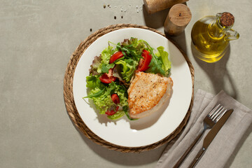 Salad with vegetables and chicken on a gray background