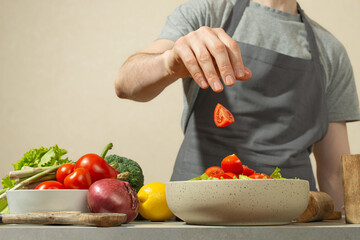 A man prepares a vegetable salad with a whole apron, close-up