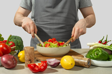 A man prepares a vegetable salad with a whole apron, close-up