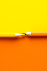 Close up of orange and yellow pencils with copy space on orange and yellow background