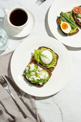 Breakfast with toast, avocado, eggs and vegetables on a gray background