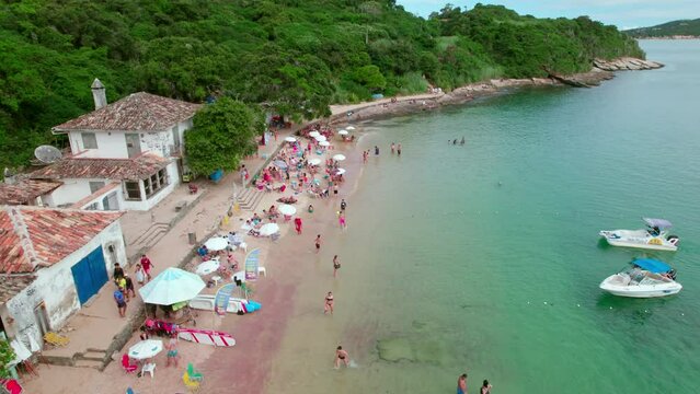 Aerial establishing orbit of Azeda beach full of people enjoying the shore and playing, B&uacute;zios, Brazil