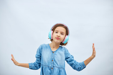 Girl teenager in casual denim dress listening to music in headphones