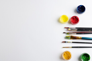 Close up of paints and brushes with copy space on white background